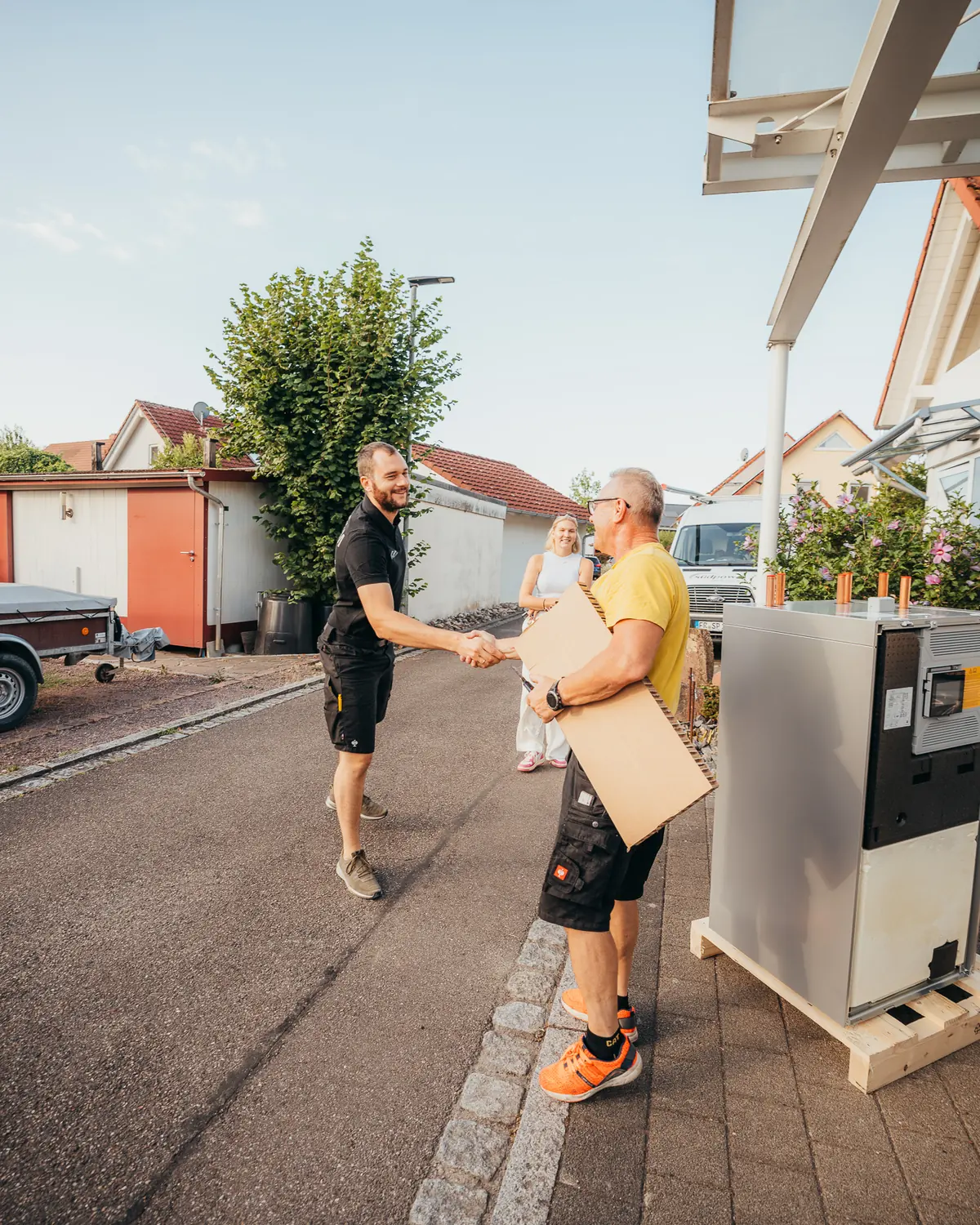 Zwei Monteure von Südpower bei der Übergabe eines Geräts vor dem Haus des Kunden