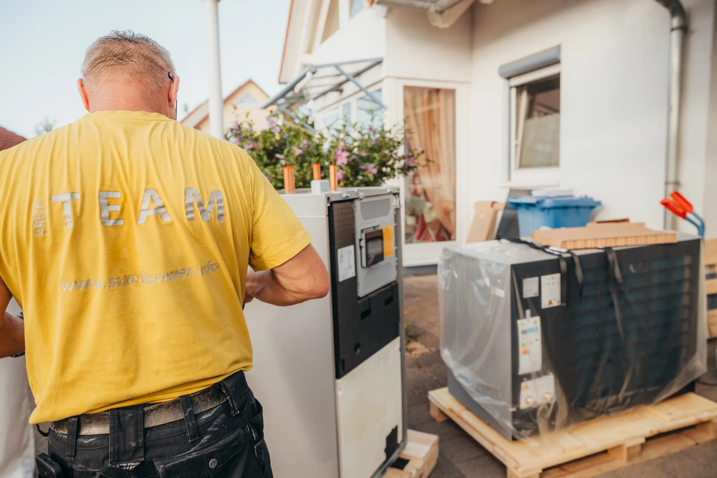 Südpower-Monteur bei der Montage einer Wärmepumpe vor einem Wohnhaus